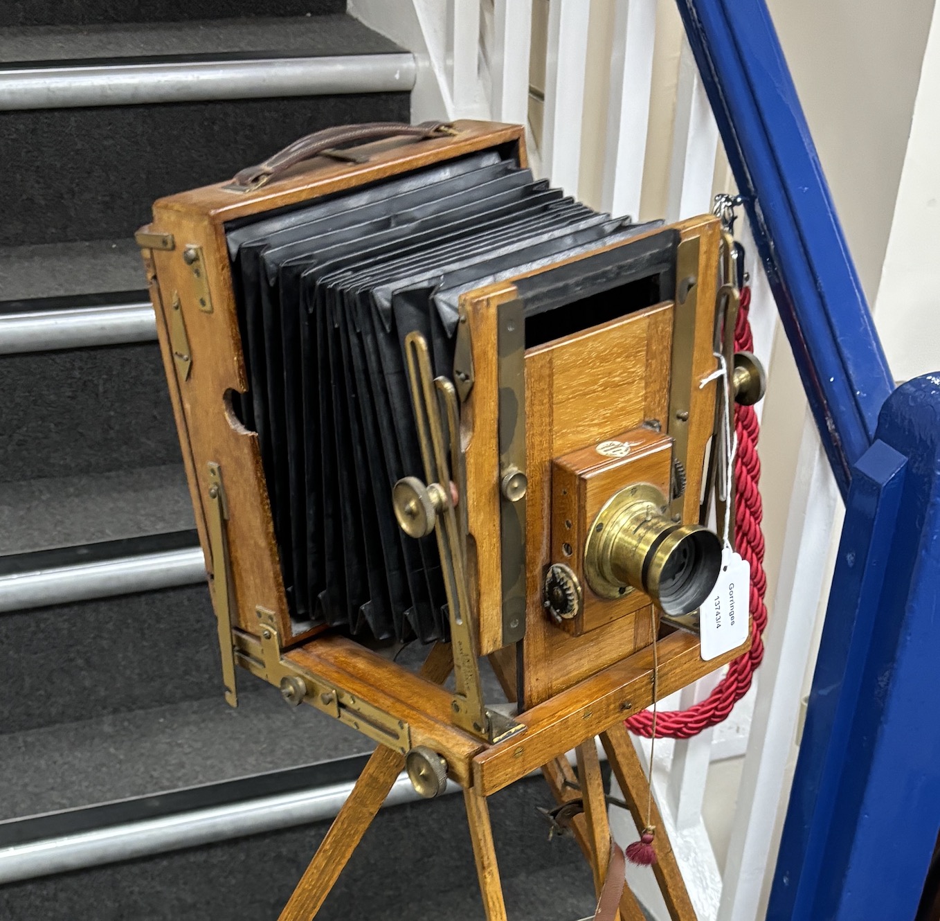 An early 20th century brass and mahogany ‘Sanderson’ half plate bellows camera by G.H.&S., London, with a lens and a shutter action by Thornton Pickard, on an oak tripod